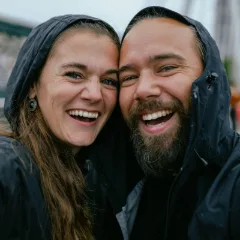 Foto original de una pareja riendo con chubasquero bajo la lluvia