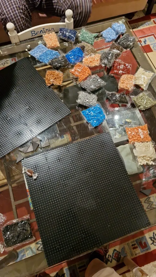Bolsas de piezas de todos los colores sobre la mesa, junto a dos placas base