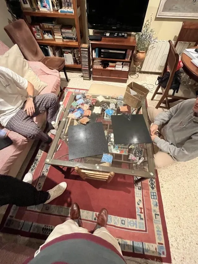 Tres amigos montando un mosaico de piezas en la mesa del salón, con placas y bolsas