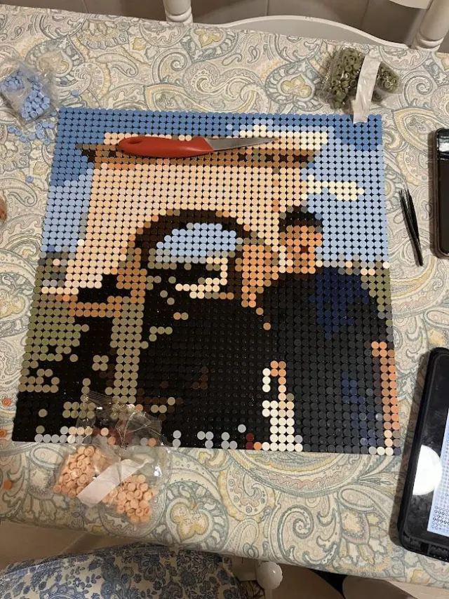 Mosaico de piezas casi terminado sobre la mesa, con las bolsas de piezas alrededor