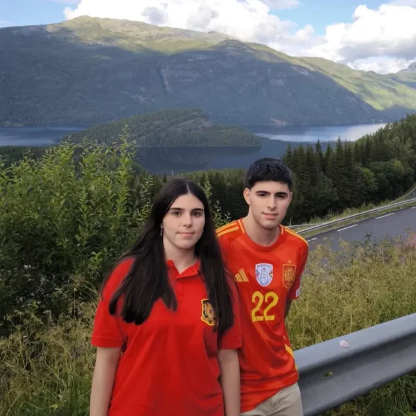 Foto original: una chica y un chico con camisetas rojas delante de un lago entre montañas